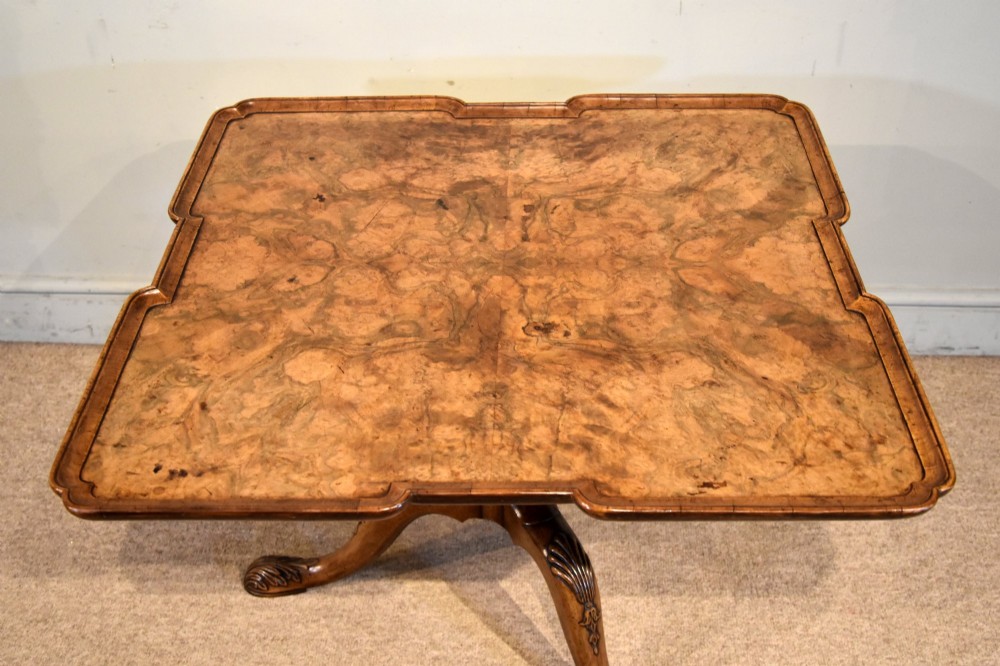 A Victorian tilt-top supper table made from burr walnut featuring a shaped top and a carved tripod pedestal base. View V