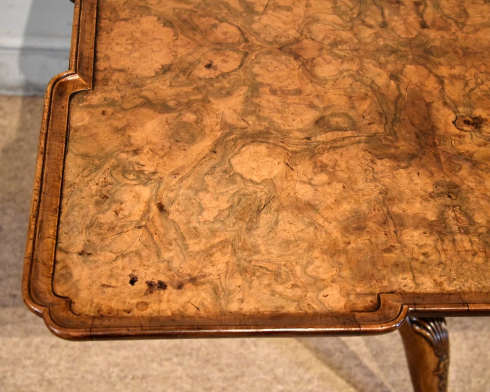 A Victorian tilt-top supper table made from burr walnut featuring a shaped top and a carved tripod pedestal base. View VI