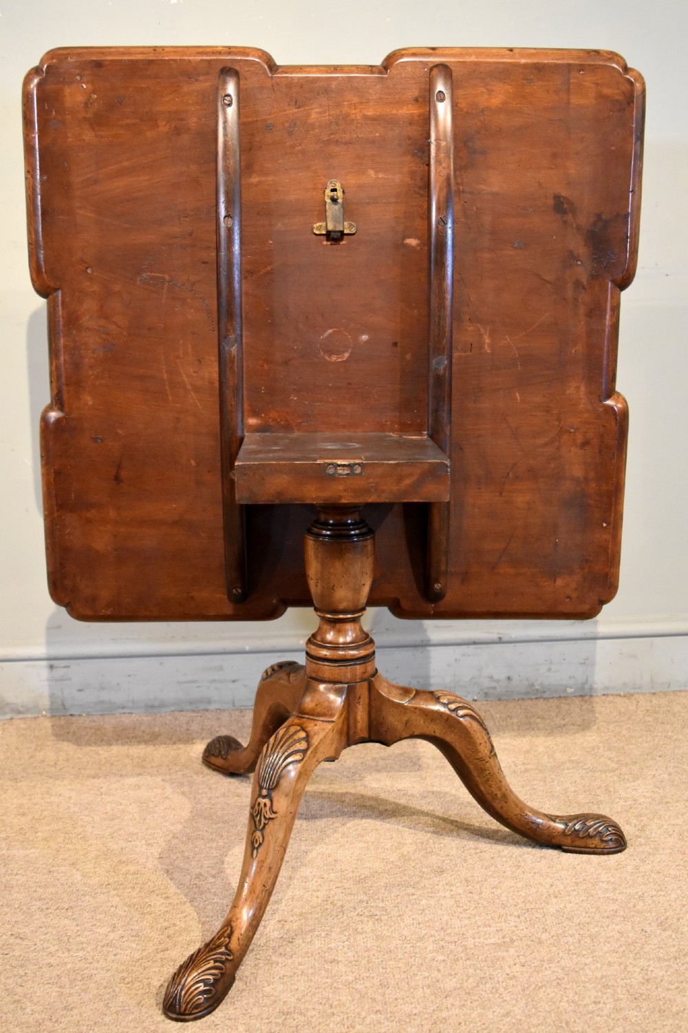 A Victorian tilt-top supper table made from burr walnut featuring a shaped top and a carved tripod pedestal base. View VII