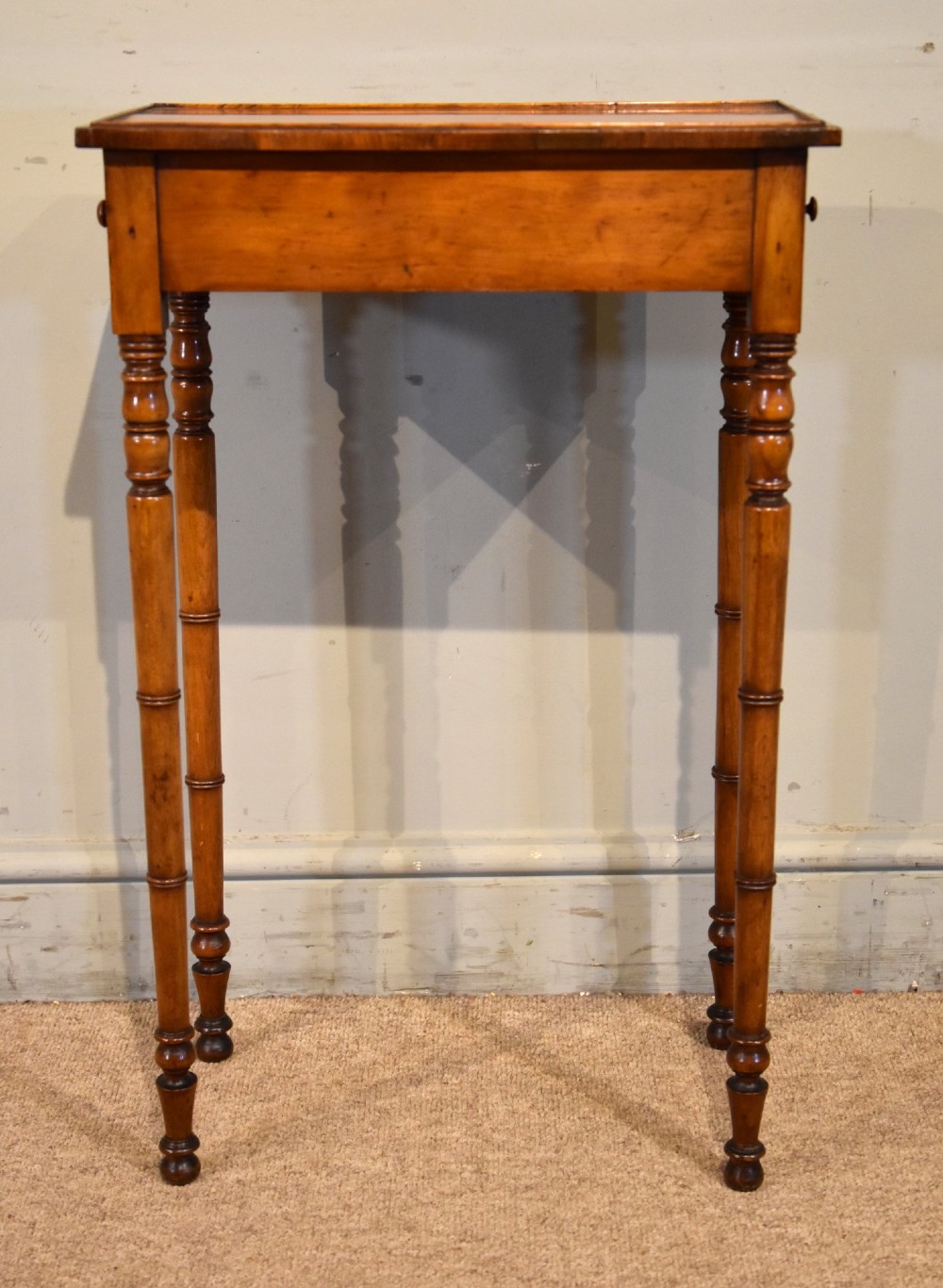 A tall, slender Regency West Indian wooden side table featuring bamboo-turned legs, a raised gallery top, and a small single end drawer. View II