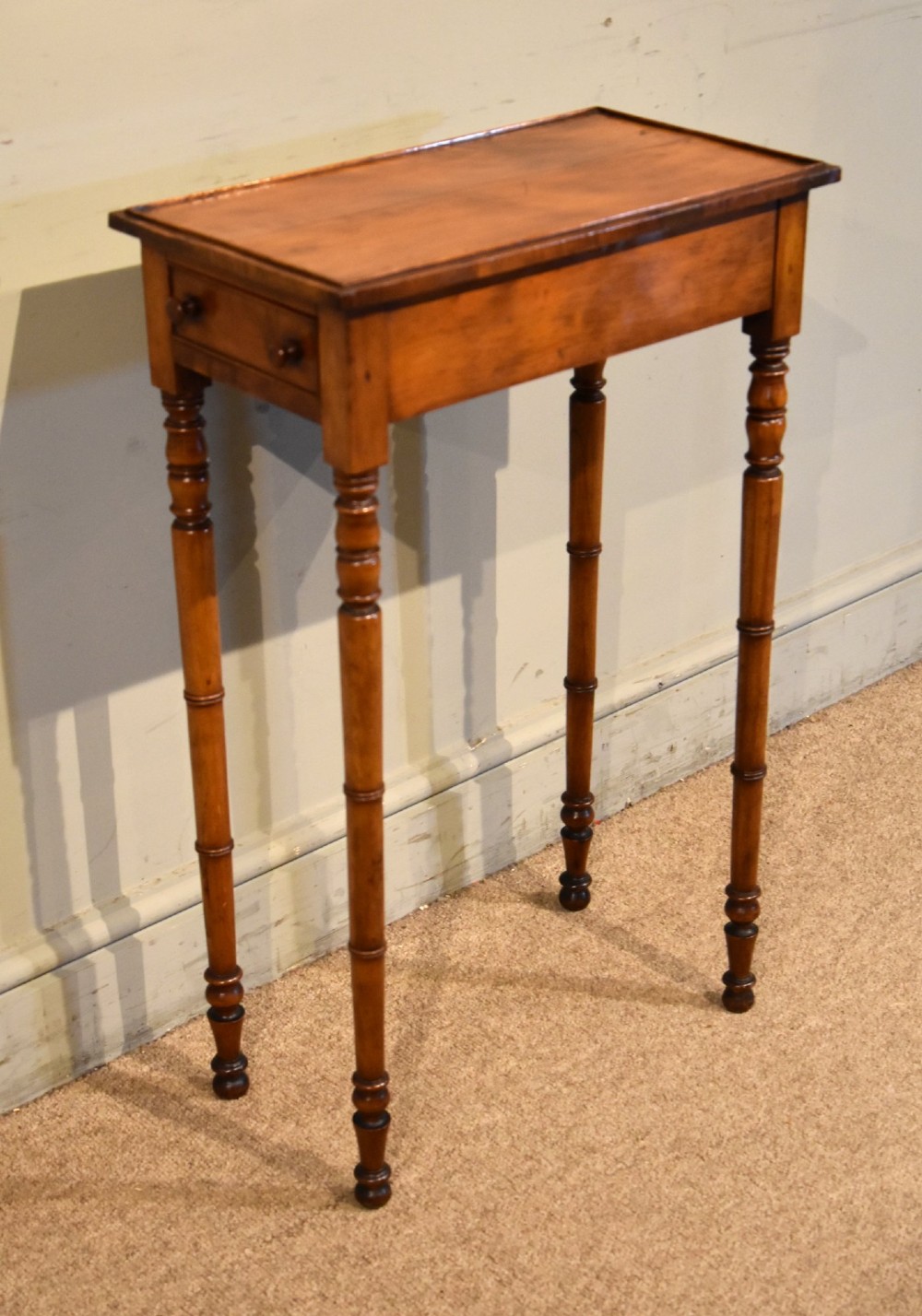 A tall, slender Regency West Indian wooden side table featuring bamboo-turned legs, a raised gallery top, and a small single end drawer. View III