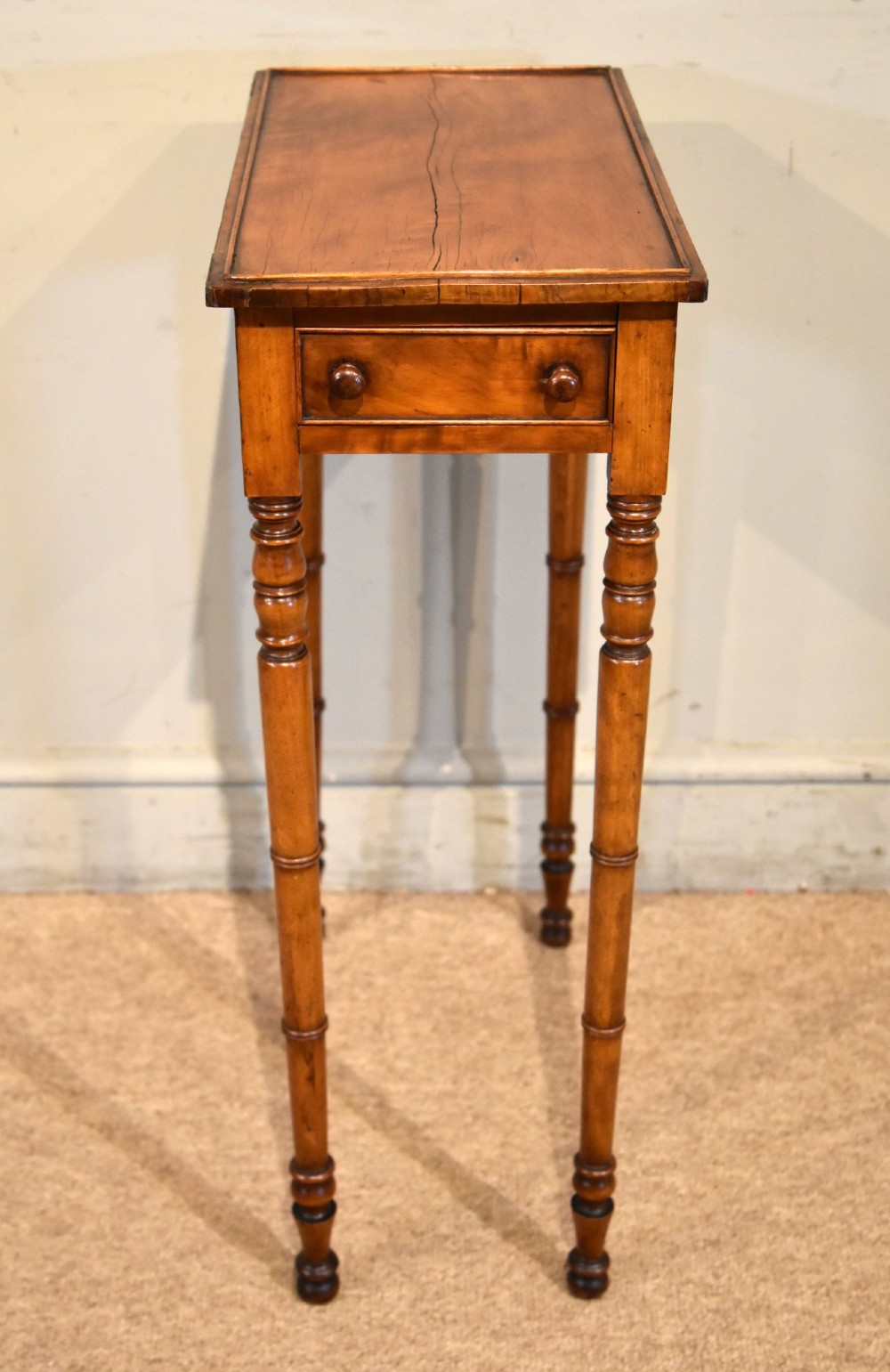 A tall, slender Regency West Indian wooden side table featuring bamboo-turned legs, a raised gallery top, and a small single end drawer. View IV