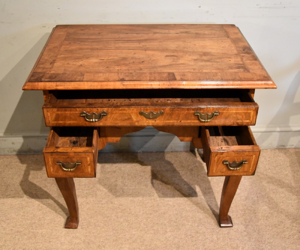 An 18th-century walnut lowboy featuring a crossbanded top, three drawers with brass drop handles, a shaped apron, and four cabriole legs. View III