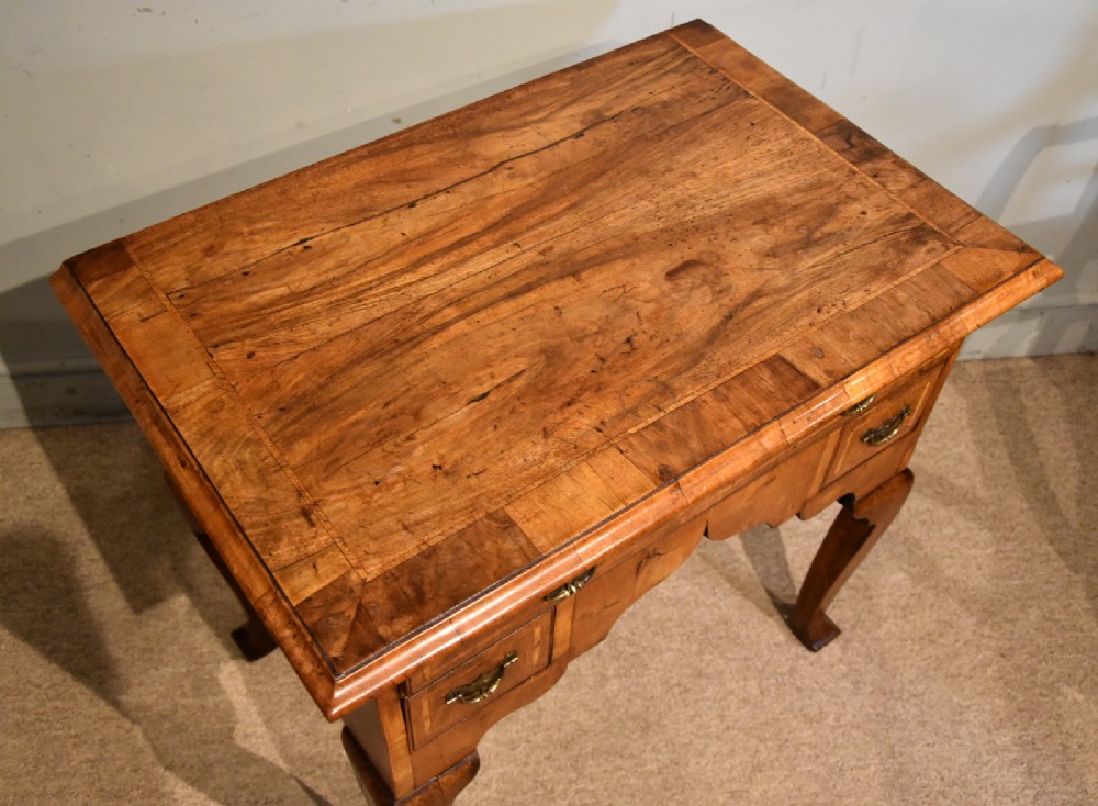 An 18th-century walnut lowboy featuring a crossbanded top, three drawers with brass drop handles, a shaped apron, and four cabriole legs. View IV