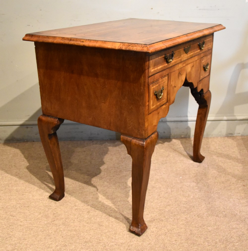An 18th-century walnut lowboy featuring a crossbanded top, three drawers with brass drop handles, a shaped apron, and four cabriole legs. View VII
