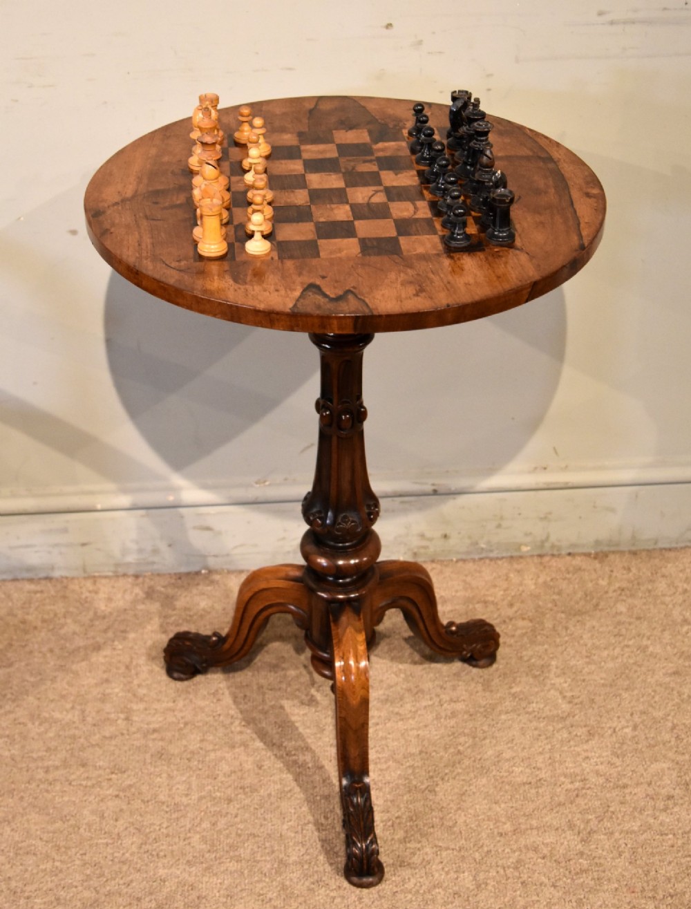 A William IV rosewood tripod games table featuring a circular top inlaid with a chess board above a carved turned stem and scroll feet. View II