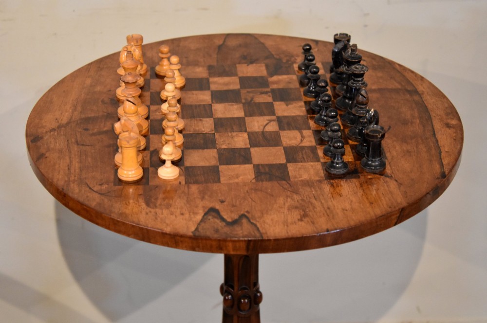 A William IV rosewood tripod games table featuring a circular top inlaid with a chess board above a carved turned stem and scroll feet. View III