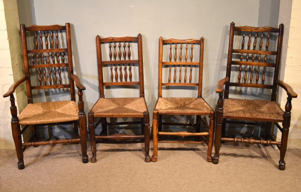 A set of ten brown oak dining chairs featuring double-tier spindle backs, woven rush seats, and turned stretchers. View III