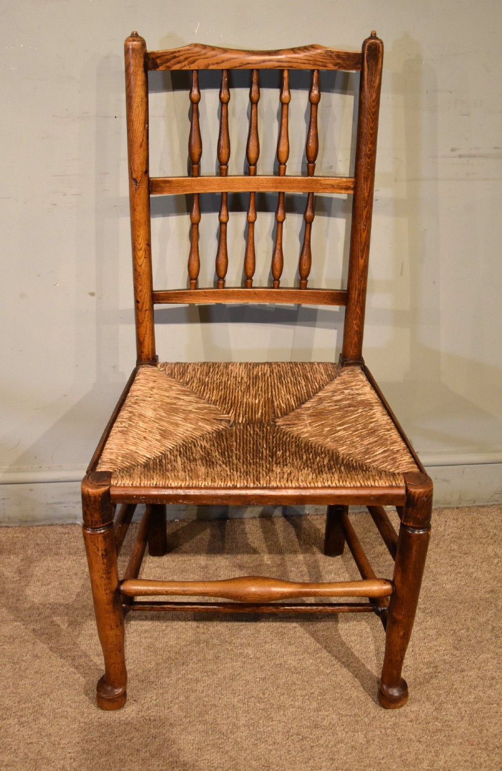 A set of ten brown oak dining chairs featuring double-tier spindle backs, woven rush seats, and turned stretchers. View IV