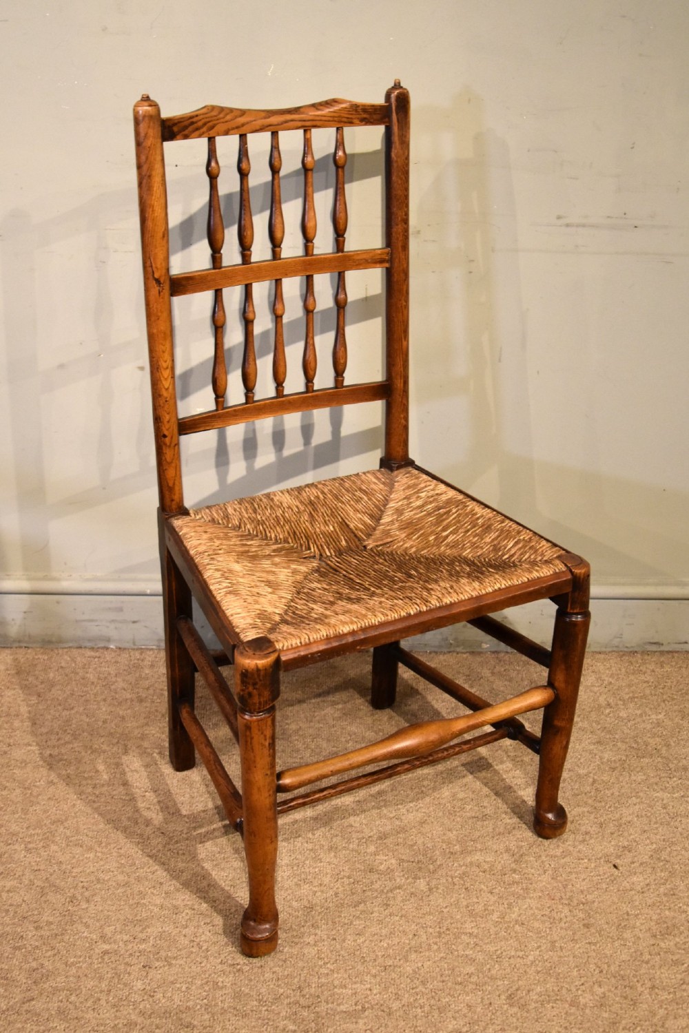 A set of ten brown oak dining chairs featuring double-tier spindle backs, woven rush seats, and turned stretchers. View V