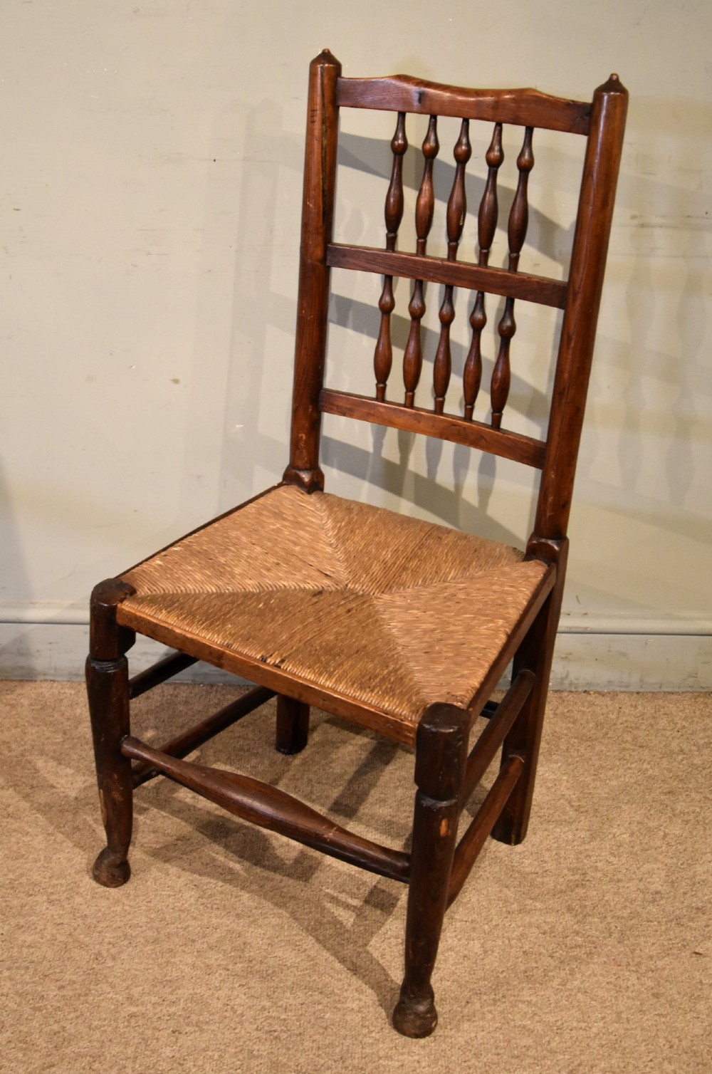 A set of ten brown oak dining chairs featuring double-tier spindle backs, woven rush seats, and turned stretchers. View VI