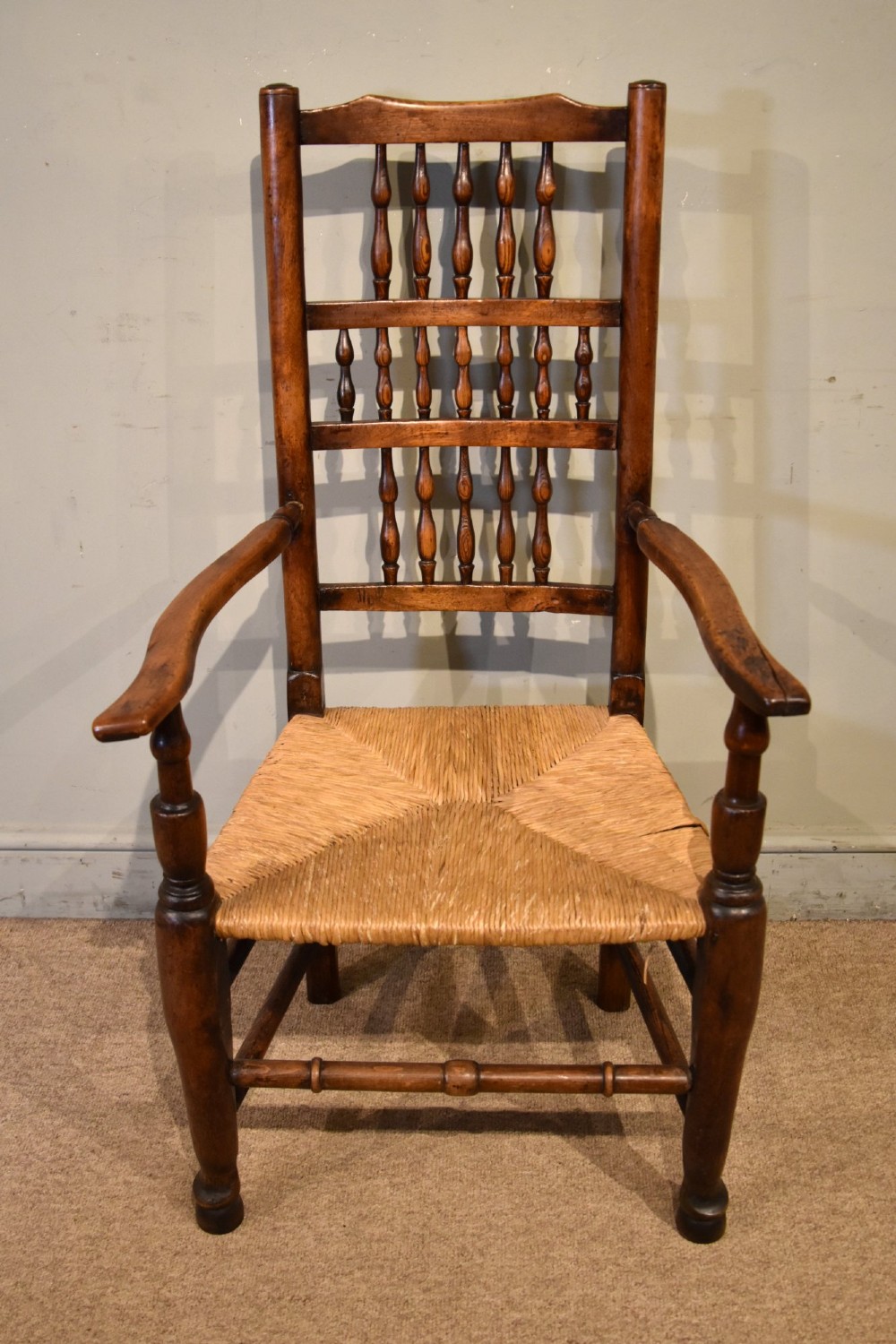 A set of ten brown oak dining chairs featuring double-tier spindle backs, woven rush seats, and turned stretchers. View VII