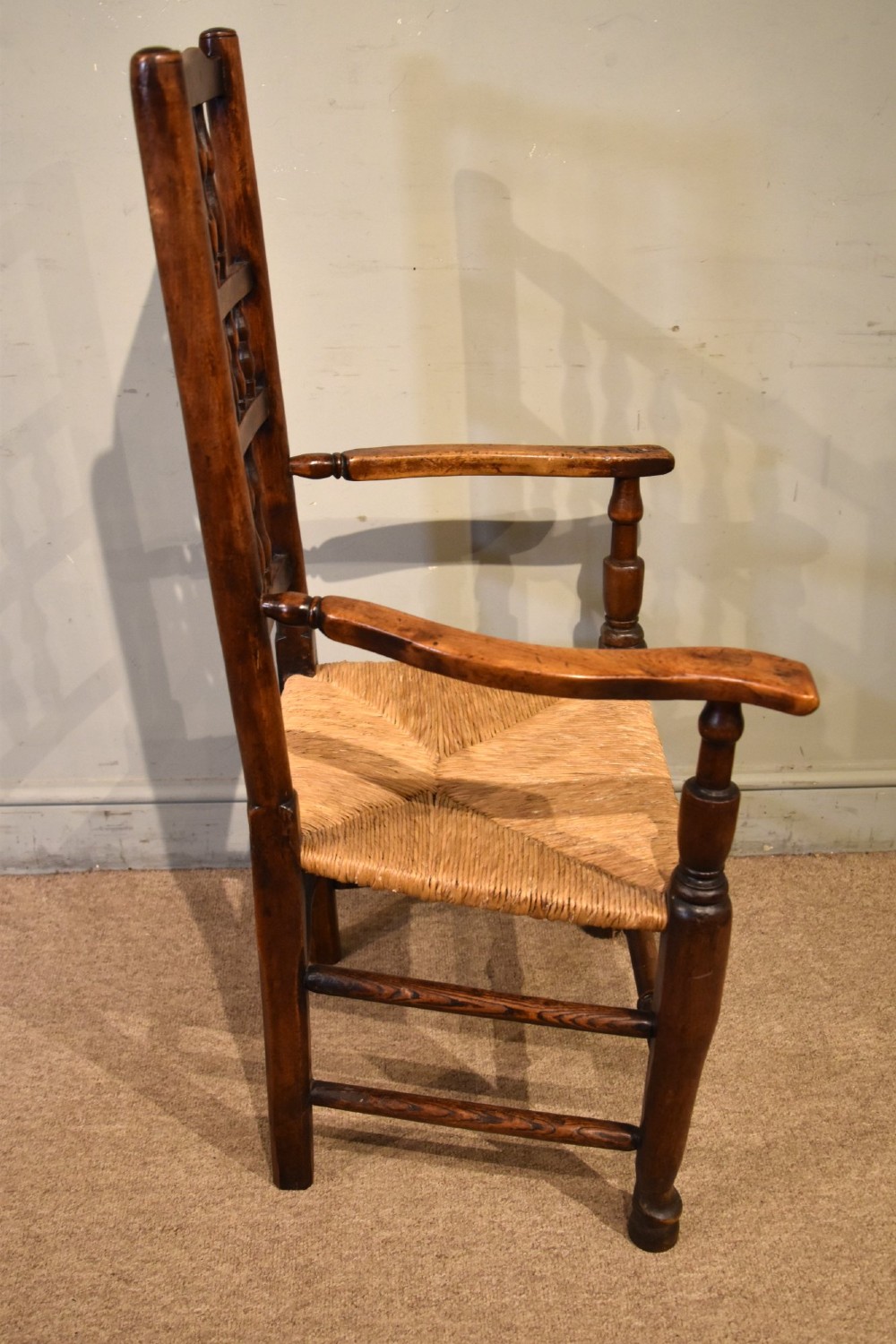 A set of ten brown oak dining chairs featuring double-tier spindle backs, woven rush seats, and turned stretchers. View IX