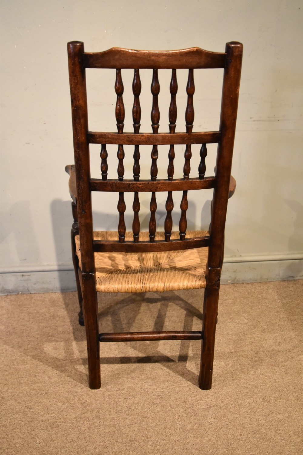 A set of ten brown oak dining chairs featuring double-tier spindle backs, woven rush seats, and turned stretchers. View X