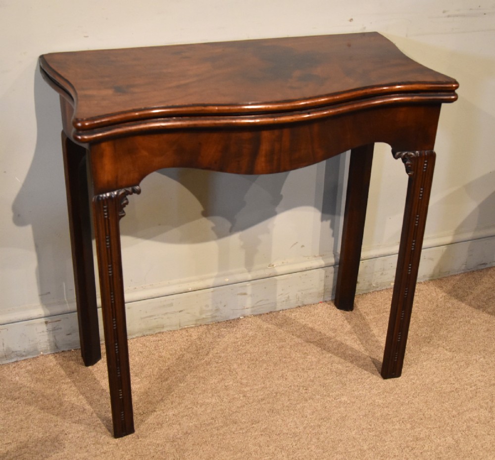 A George III Cuban mahogany fold-over tea table featuring a serpentine front, carved corner brackets, and fluted legs. View III