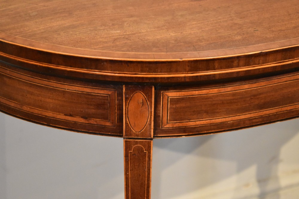 A George III mahogany demi-lune card table featuring boxwood stringing inlay and square tapered legs. View II