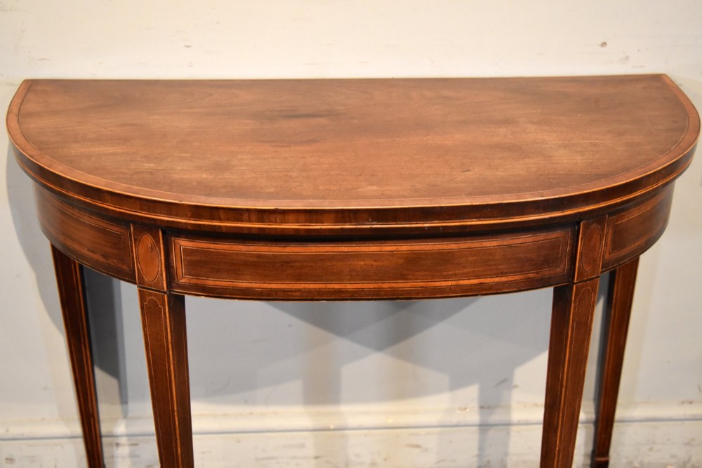 A George III mahogany demi-lune card table featuring boxwood stringing inlay and square tapered legs. View IV