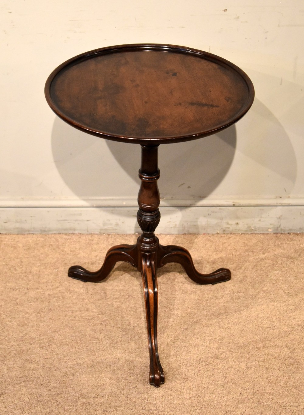 An 18th-century Hepplewhite mahogany wine table featuring a circular dish top, turned central pedestal, and tripod legs.