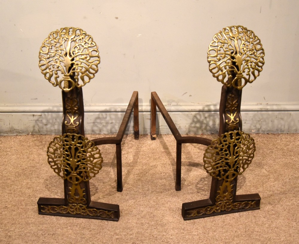 A pair of 19th-century brass and cast iron fire dogs featuring pierced circular foliate brass finials on dark iron uprights with horizontal log billets.