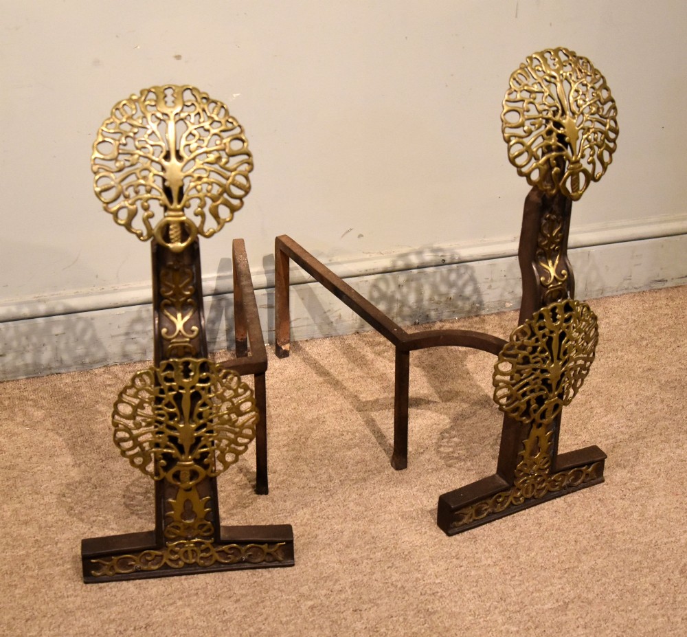 A pair of 19th-century brass and cast iron fire dogs featuring pierced circular foliate brass finials on dark iron uprights with horizontal log billets. View II