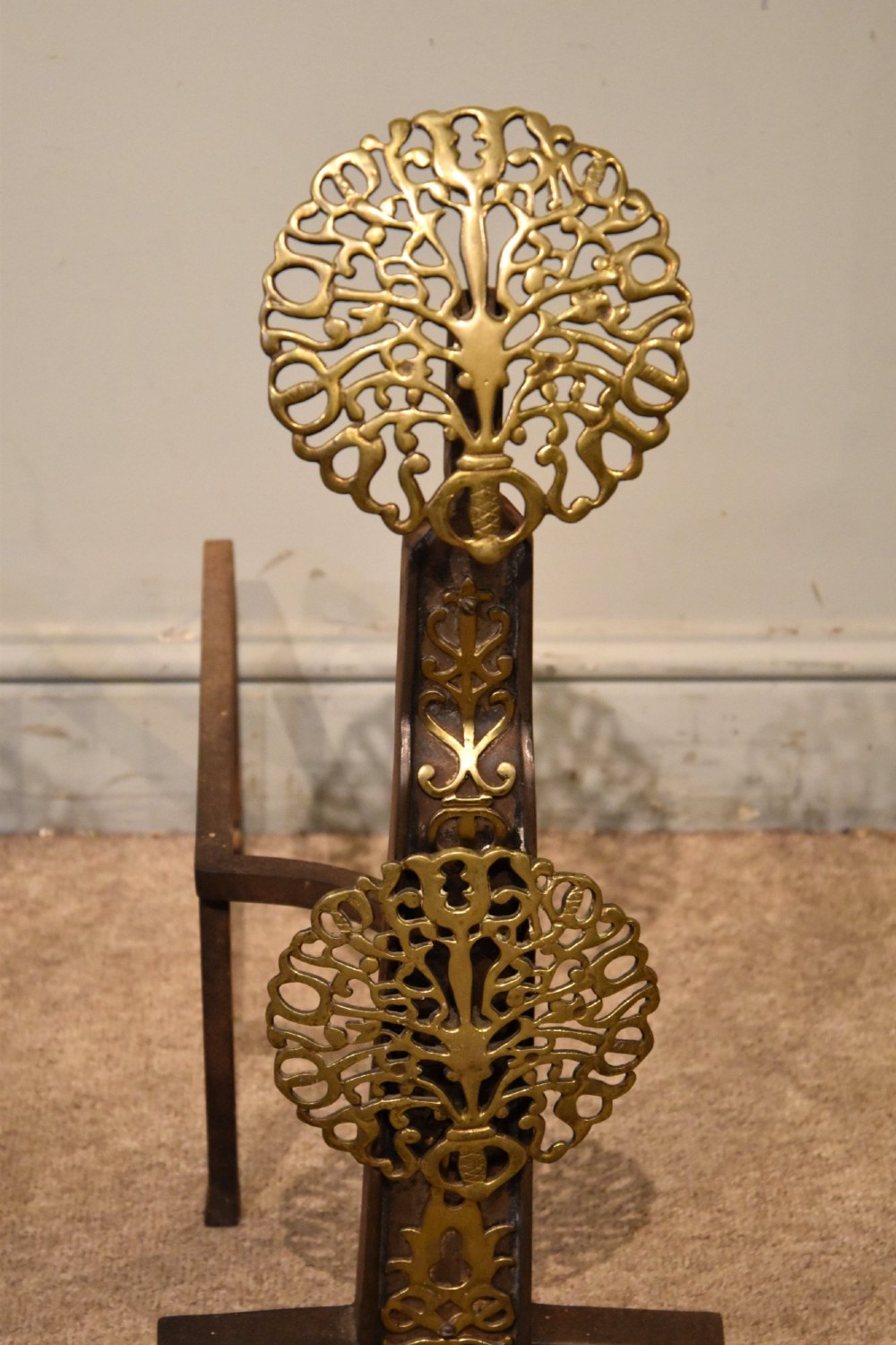 A pair of 19th-century brass and cast iron fire dogs featuring pierced circular foliate brass finials on dark iron uprights with horizontal log billets. View IV