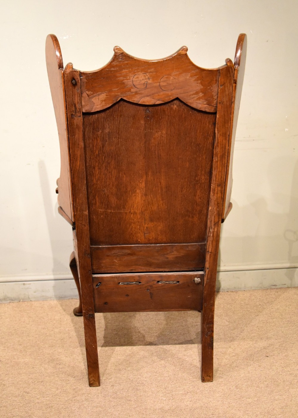 An 18th-century solid oak wingback armchair with a fielded panel back, shaped wings, cabriole front legs, and an aged green cushion. View VII