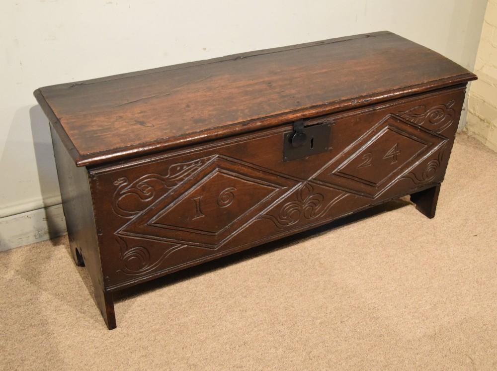 A 17th-century dark oak six-plank coffer featuring carved lozenge patterns containing the date 1624 and a central iron lockplate. View V