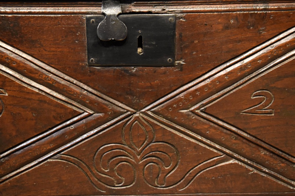 A 17th-century dark oak six-plank coffer featuring carved lozenge patterns containing the date 1624 and a central iron lockplate. View VII