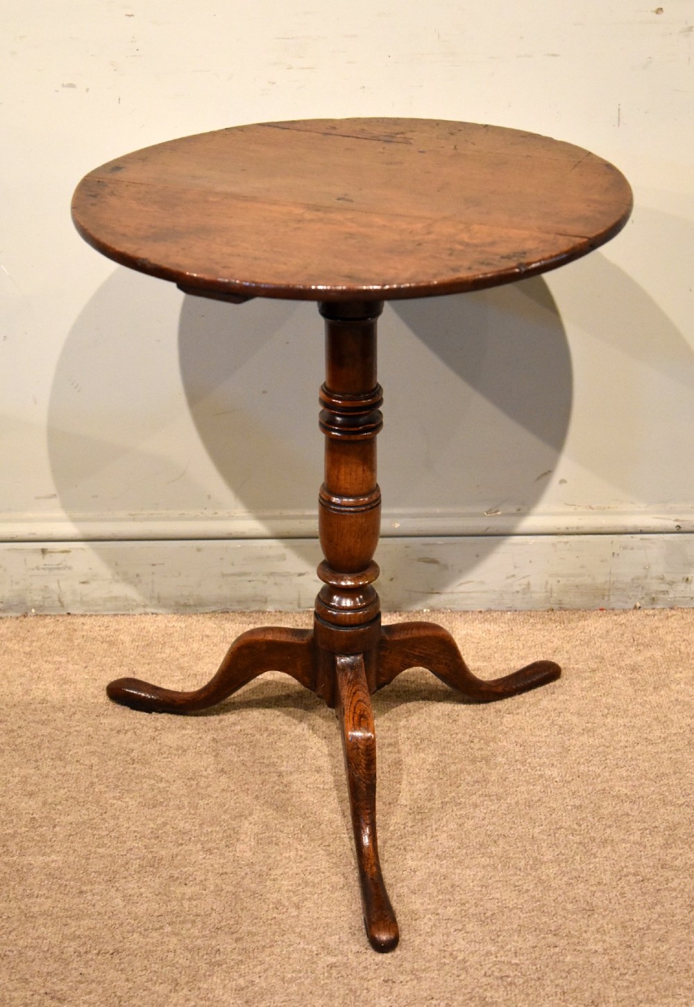 An 18th-century dark oak tripod wine table featuring a circular top, a central turned column stem, and three downcurved legs. View II