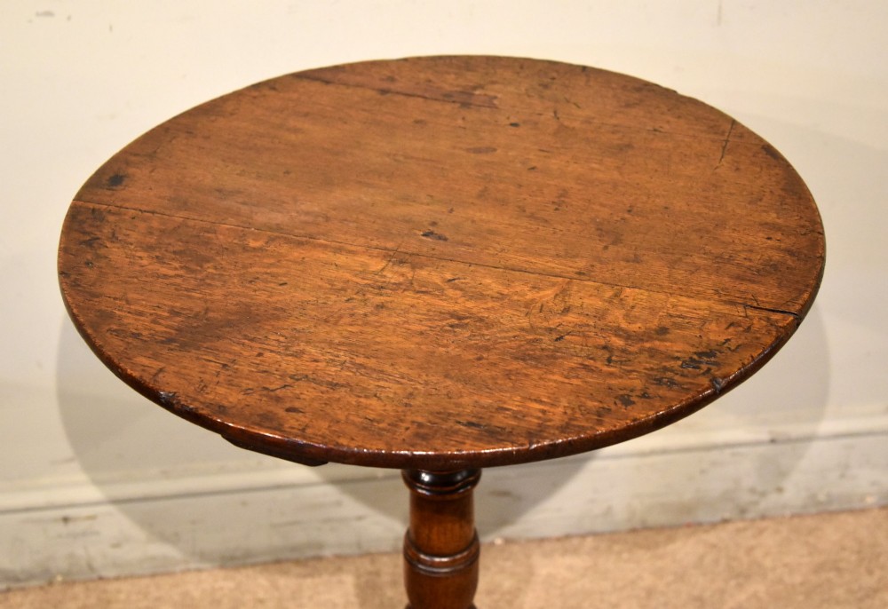 An 18th-century dark oak tripod wine table featuring a circular top, a central turned column stem, and three downcurved legs. View III