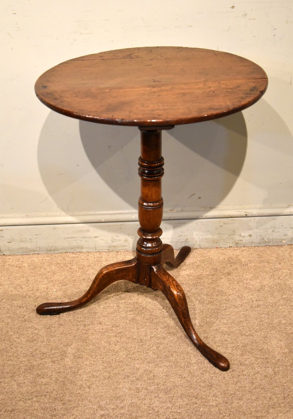 An 18th-century dark oak tripod wine table featuring a circular top, a central turned column stem, and three downcurved legs. View IV