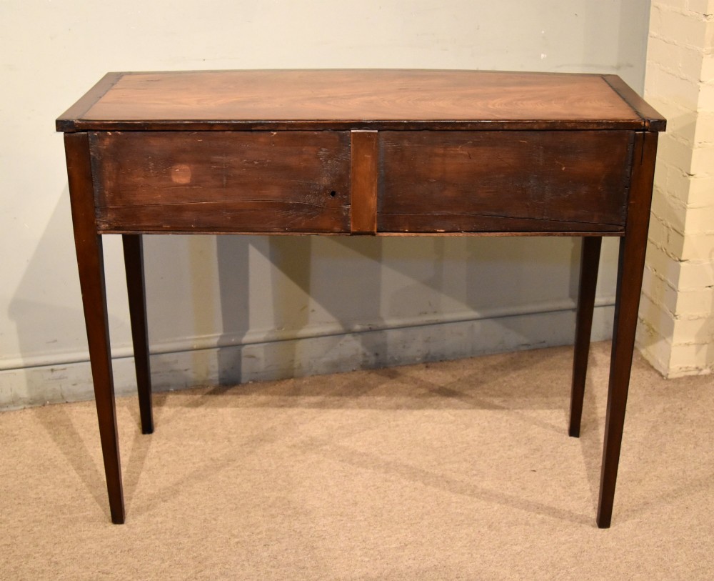 A George III bowfront mahogany serving table featuring two drawers with brass oval handles and slender tapered legs. View VIII