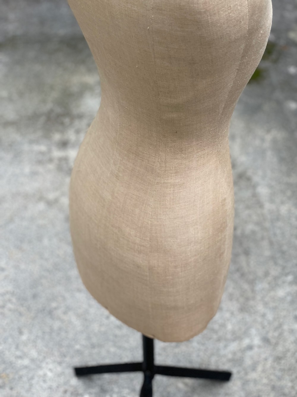 A fabric-covered female tailors dummy torso featuring stitched neutral linen upholstery and a dark turned neck finial. View V