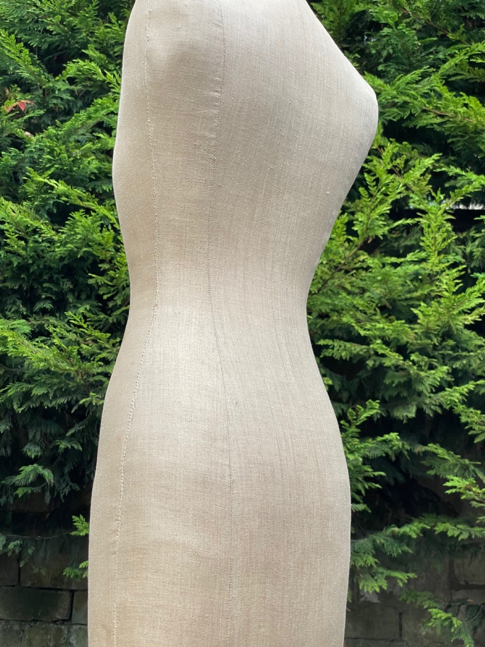 A fabric-covered female tailors dummy torso featuring stitched neutral linen upholstery and a dark turned neck finial. View IX