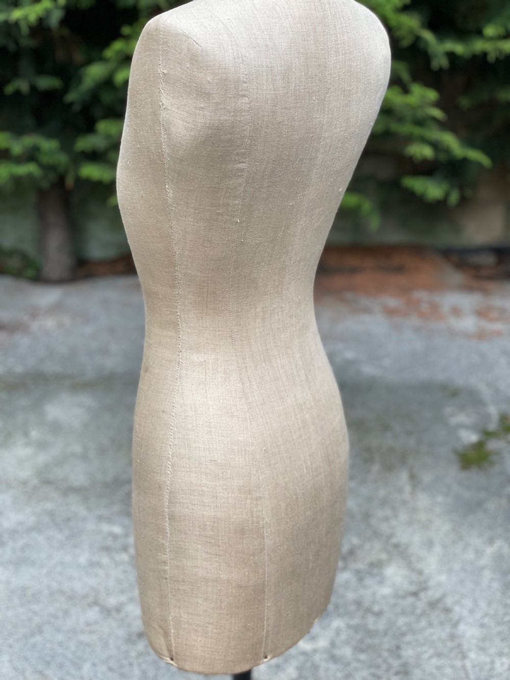 A fabric-covered female tailors dummy torso featuring stitched neutral linen upholstery and a dark turned neck finial. View XI