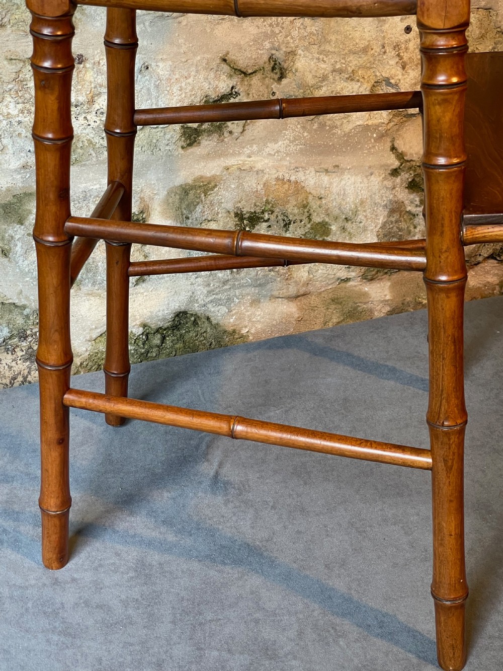 An antique Victorian faux bamboo turned wood childs high chair featuring a woven cane seat and integrated footrest. View VI