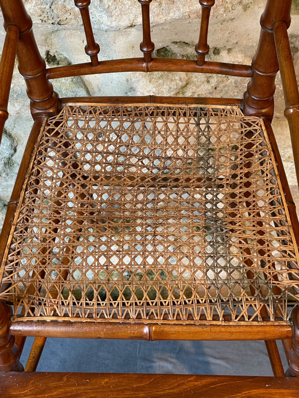 An antique Victorian faux bamboo turned wood childs high chair featuring a woven cane seat and integrated footrest. View VIII