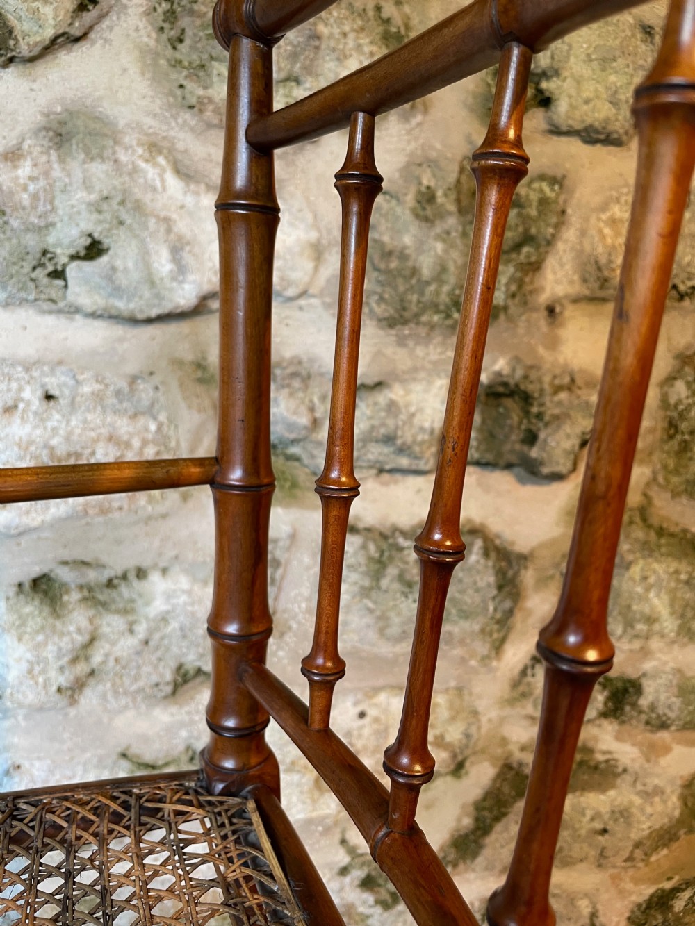 An antique Victorian faux bamboo turned wood childs high chair featuring a woven cane seat and integrated footrest. View XII