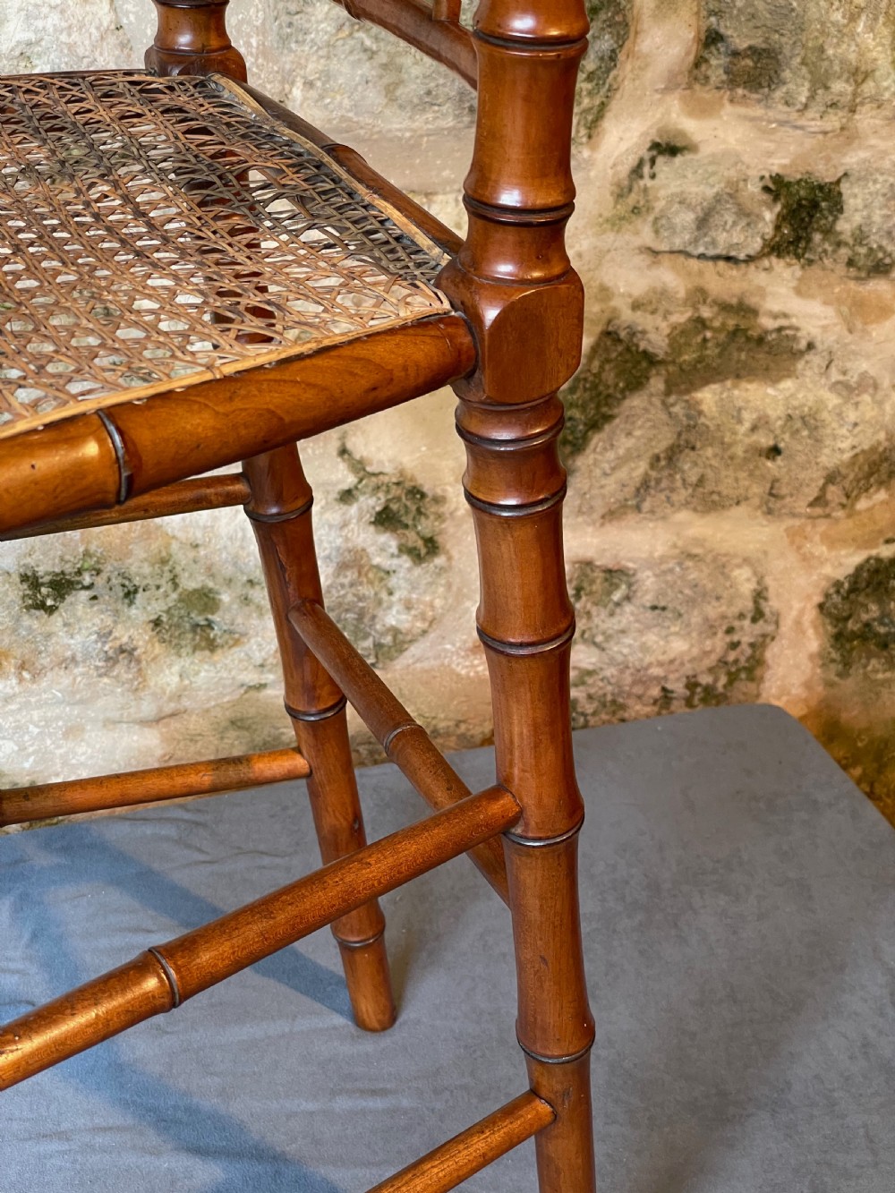 An antique Victorian faux bamboo turned wood childs high chair featuring a woven cane seat and integrated footrest. View XIV
