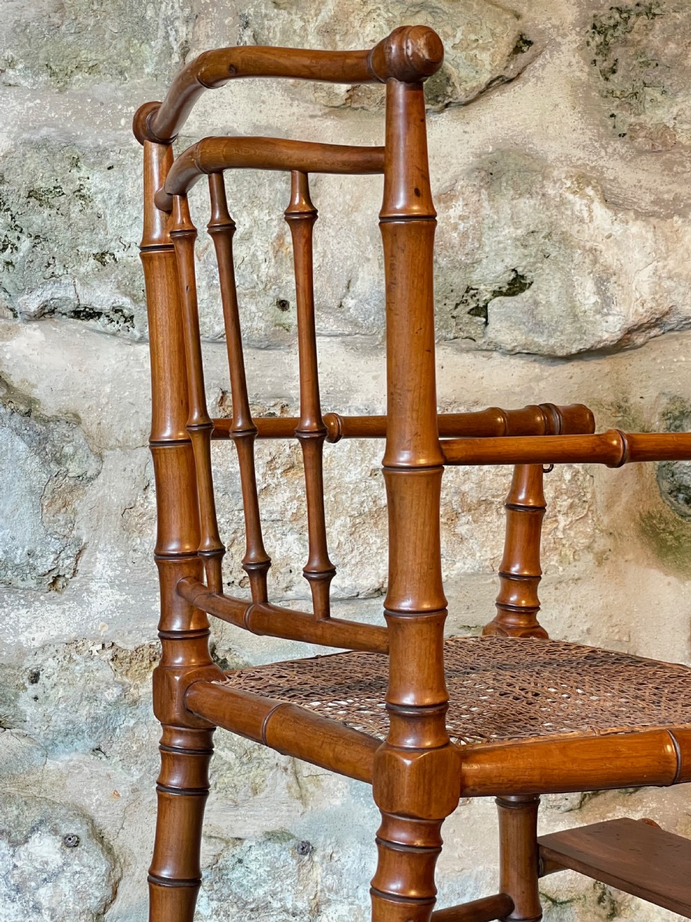 An antique Victorian faux bamboo turned wood childs high chair featuring a woven cane seat and integrated footrest. View XIX