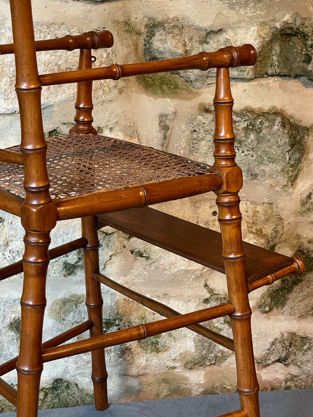 An antique Victorian faux bamboo turned wood childs high chair featuring a woven cane seat and integrated footrest. View XX