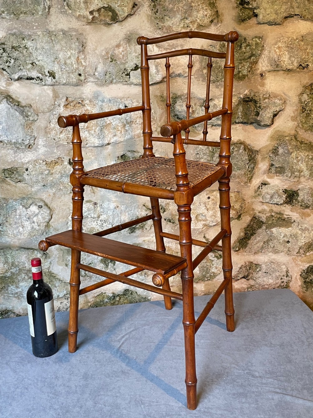 An antique Victorian faux bamboo turned wood childs high chair featuring a woven cane seat and integrated footrest. View XXII