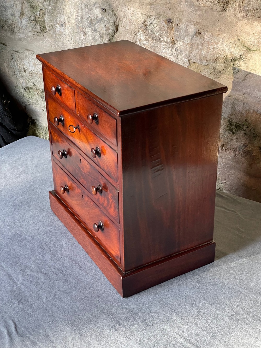 A miniature Victorian mahogany chest of drawers with two short over three long drawers, turned wooden knobs, and keyholes. View VI