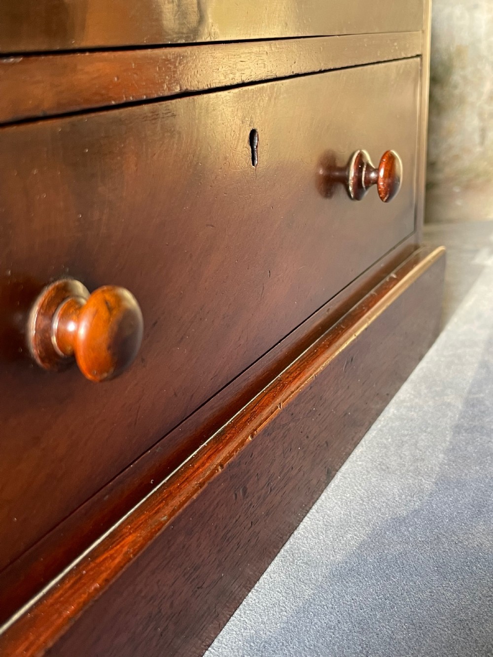 A miniature Victorian mahogany chest of drawers with two short over three long drawers, turned wooden knobs, and keyholes. View VIII