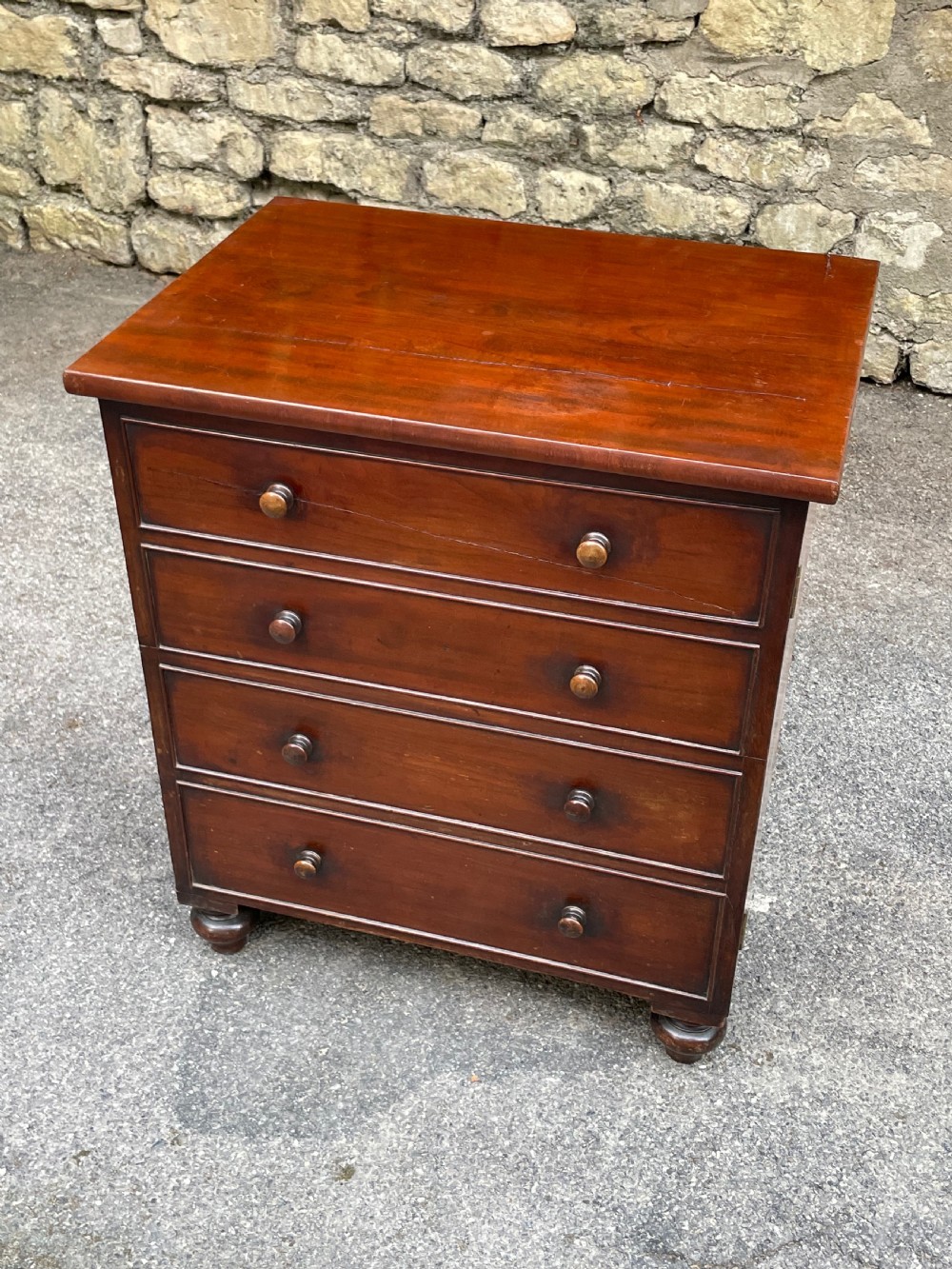 A Victorian warm brown wooden chest featuring four horizontal drawers with matching wooden knob handles and turned feet. View III