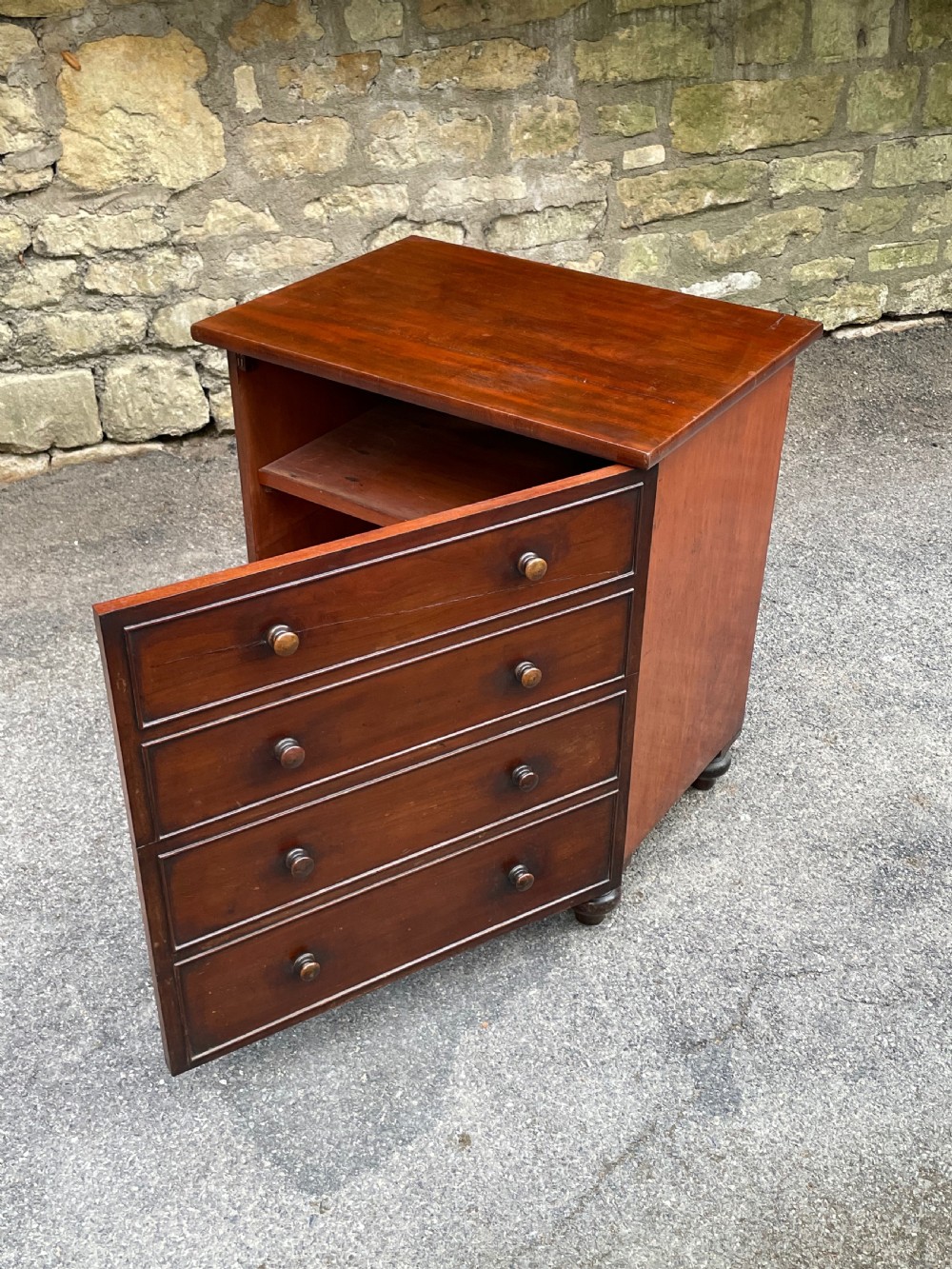 A Victorian warm brown wooden chest featuring four horizontal drawers with matching wooden knob handles and turned feet. View V