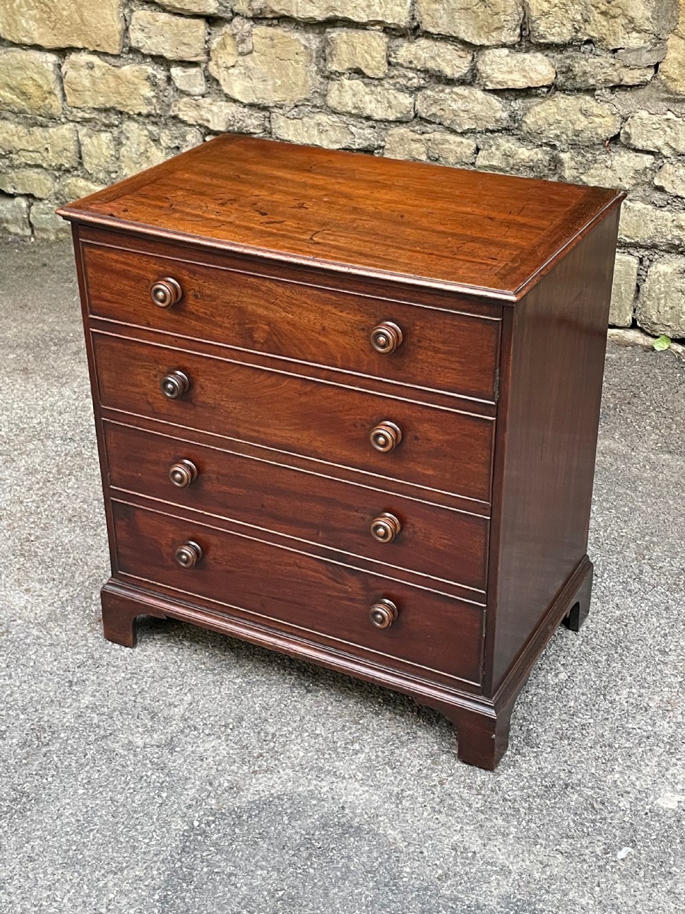 A Georgian mahogany chest featuring four drawer fronts with turned wooden handles and bracket feet.