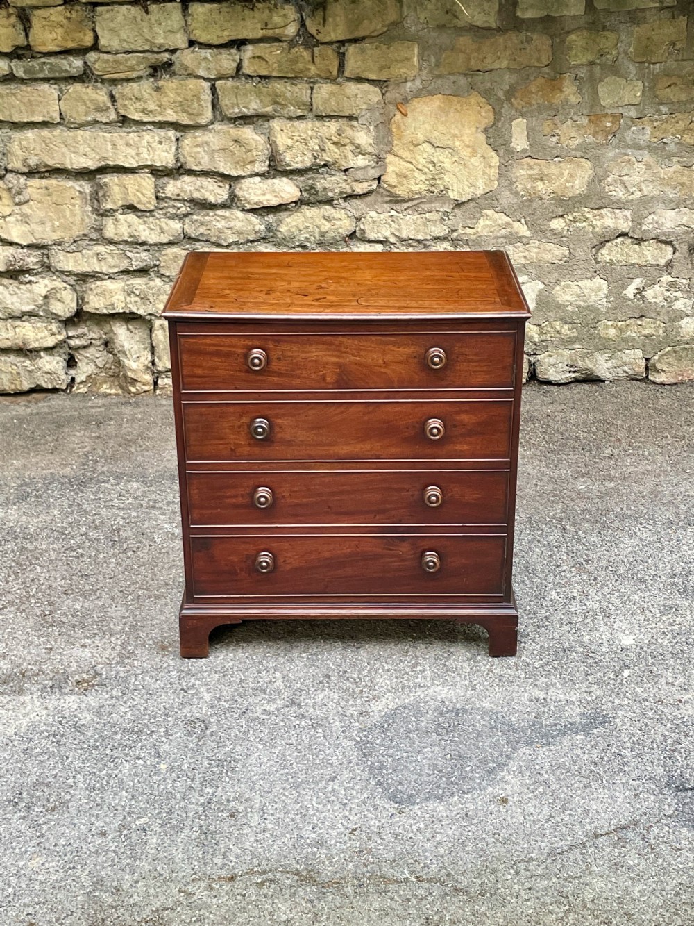 A Georgian mahogany chest featuring four drawer fronts with turned wooden handles and bracket feet. View II