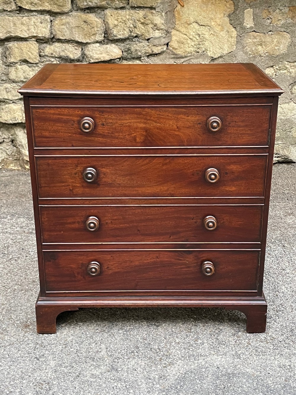A Georgian mahogany chest featuring four drawer fronts with turned wooden handles and bracket feet. View III