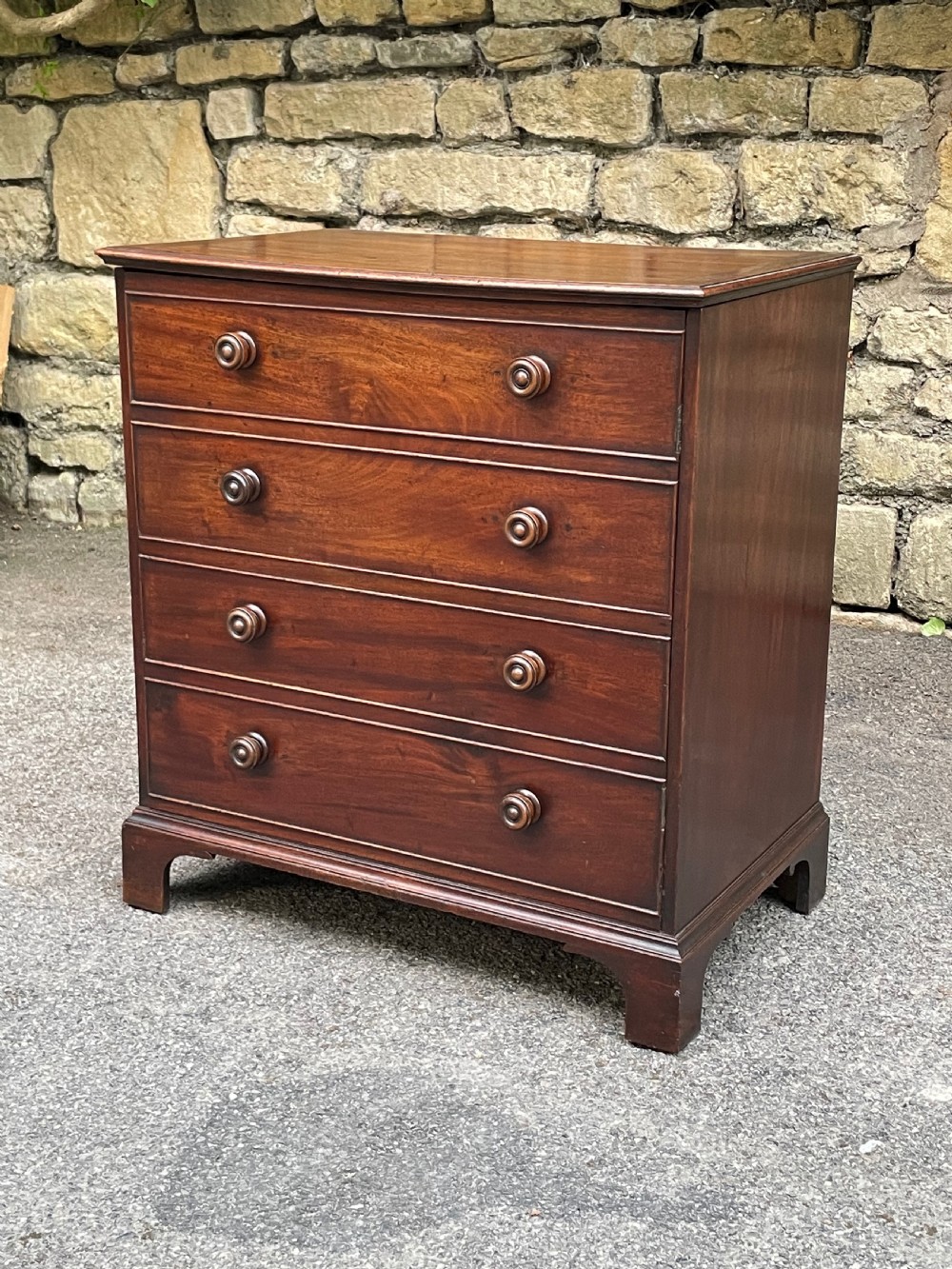 A Georgian mahogany chest featuring four drawer fronts with turned wooden handles and bracket feet. View V